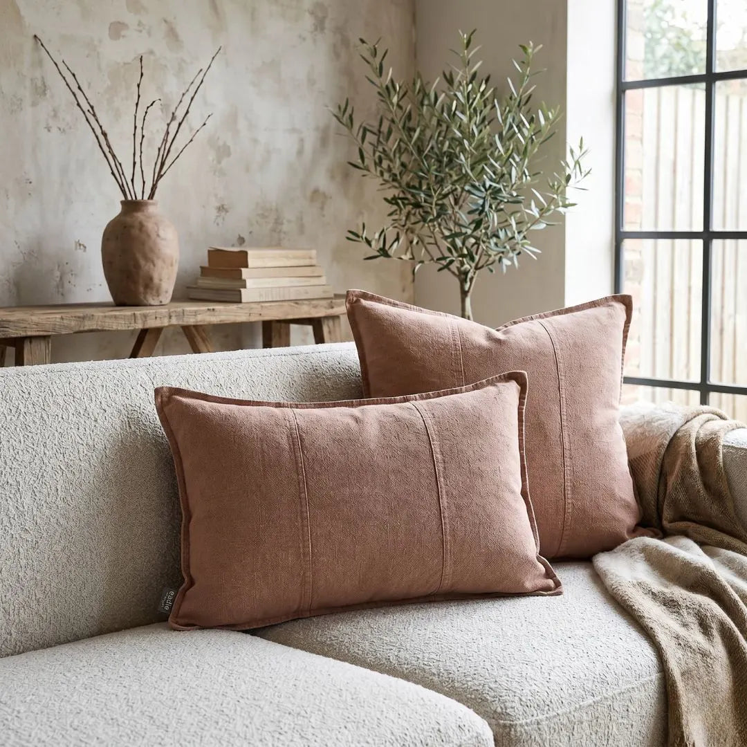 Cozy living room with a beige sofa, brown cushions, and a wooden side table with books and a vase.