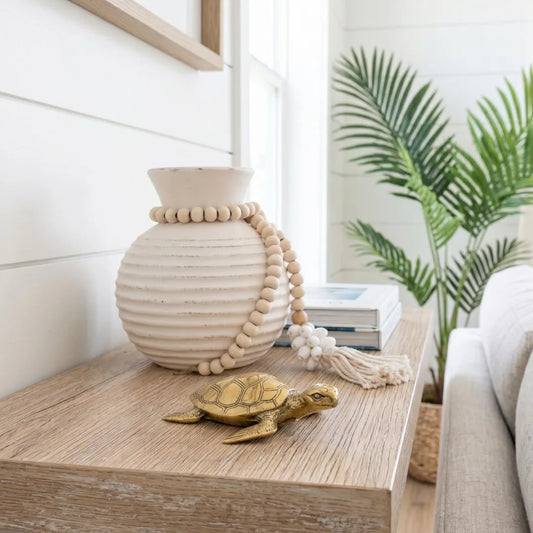 Decorative turtle figurine and ceramic vase on a wooden surface with a plant in the background