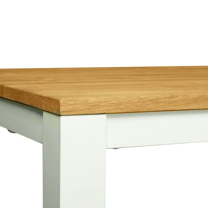 A close-up of a table corner showing a light brown wood grain top and a white painted metal frame, isolated on a white background.