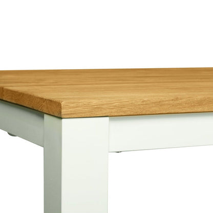 A close-up of a table corner showing a light brown wood grain top and a white painted metal frame, isolated on a white background.