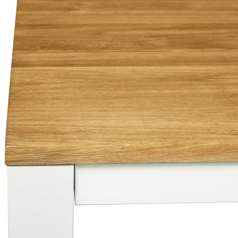 Close-up of a modern table corner showing a light oak wood grain top and a white metal leg on a plain white background.