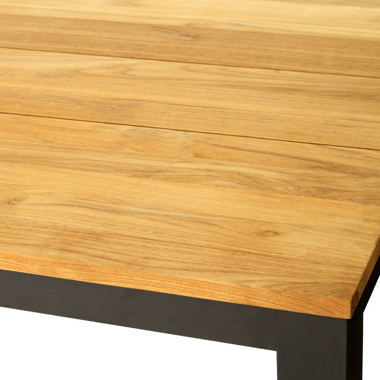 A close-up of a wooden tabletop with a light natural wood grain finish and a dark metal base, shown on a plain white background.