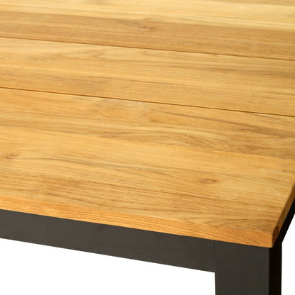A close-up of a wooden tabletop with a light natural wood grain finish and a dark metal base, shown on a plain white background.
