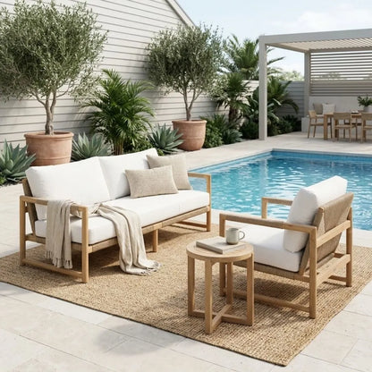Outdoor patio set with wooden furniture and white cushions by a pool.