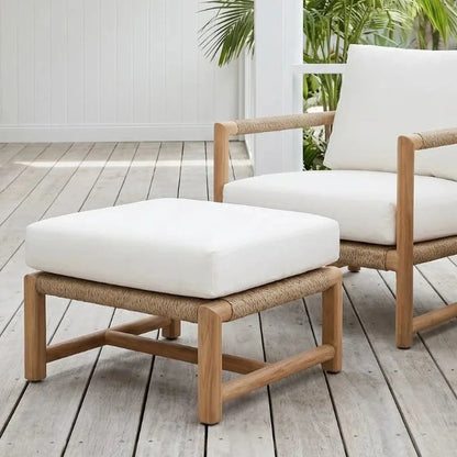Wooden outdoor furniture set with white cushions on a wooden deck.