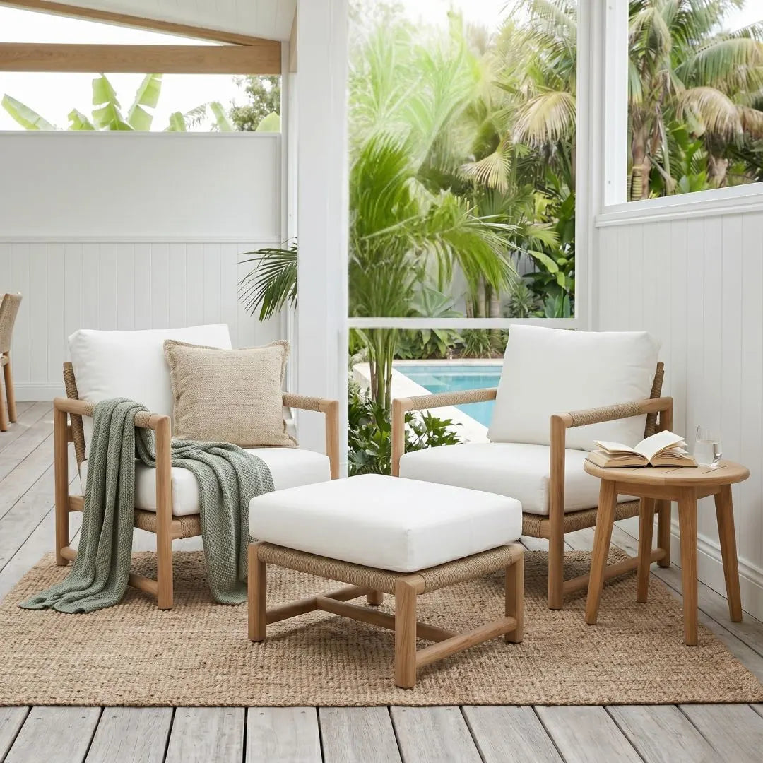 Outdoor patio furniture set with white cushions, wooden frames, and a small table on a deck.