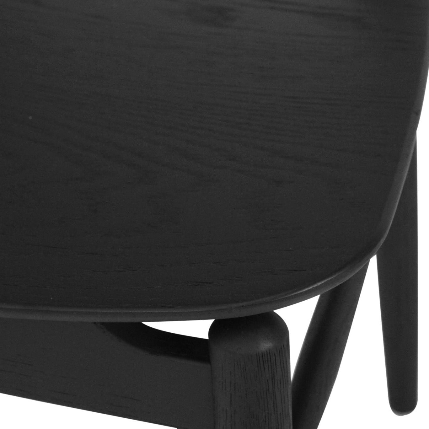 Close-up detail of a black wooden table showing the curved top surface, grain texture, and part of the leg and support structure against a white background.