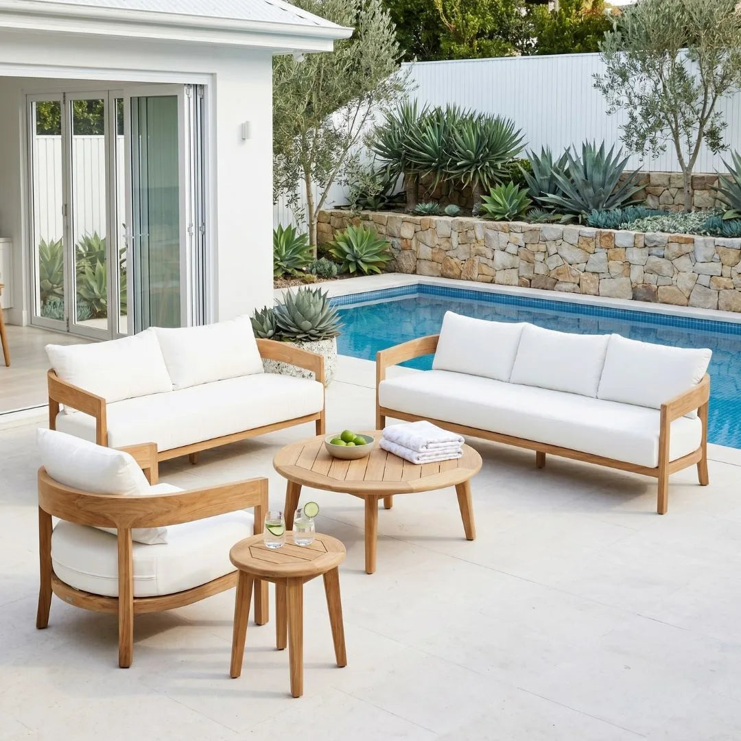 Outdoor patio set with wooden frames and white cushions by a pool.