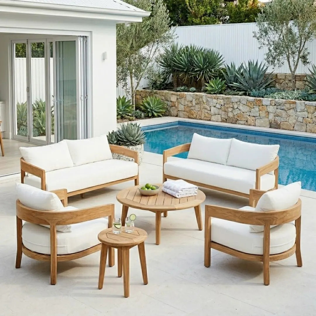 Outdoor patio furniture set with wooden frames and white cushions by a pool.
