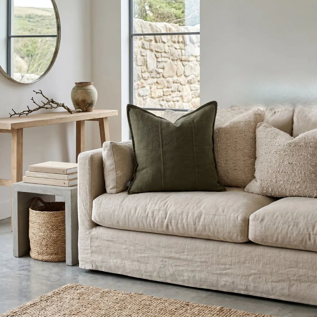 Beige sofa with decorative pillows in a living room setting.