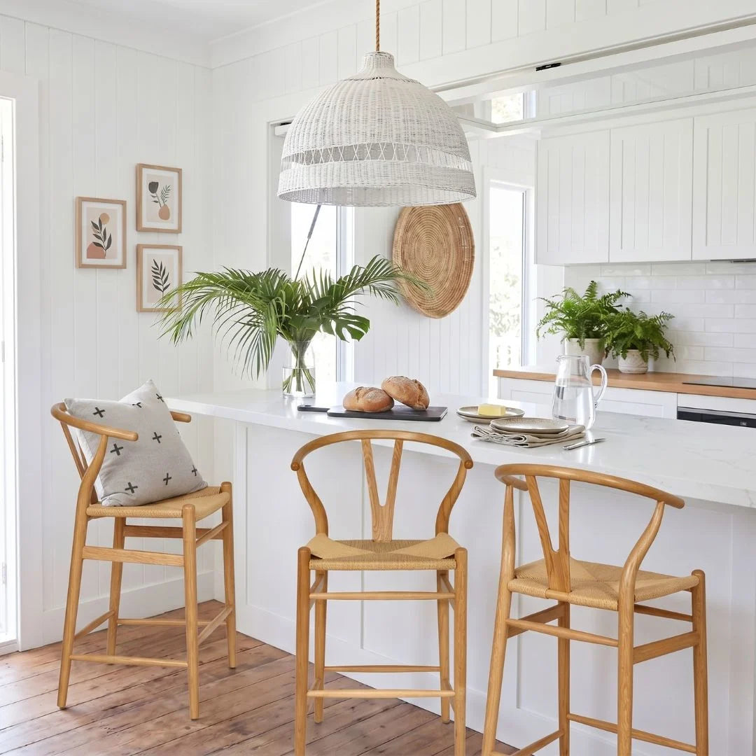 Modern kitchen with white island, wooden chairs, and decorative elements.