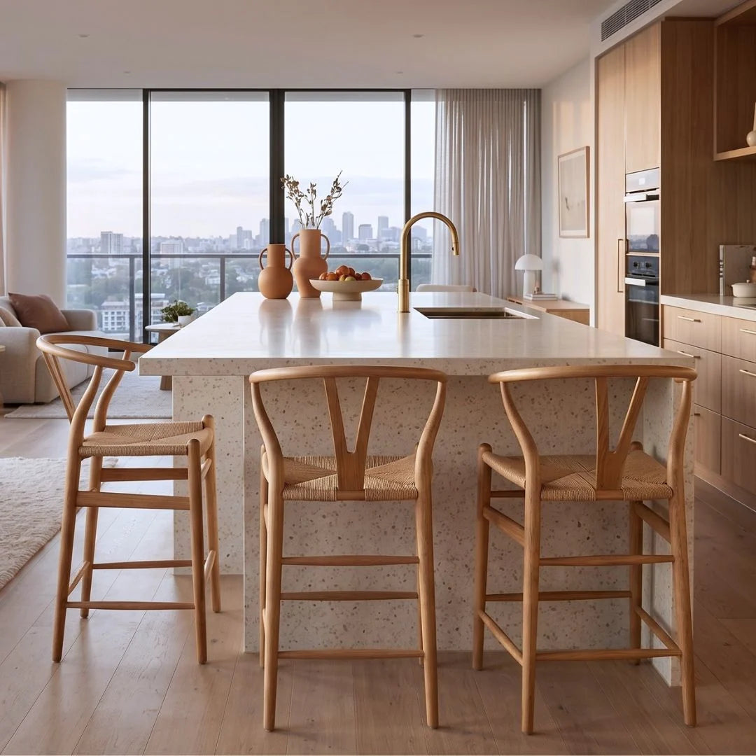 Modern kitchen with a island and wooden bar stools, large windows showing a cityscape.
