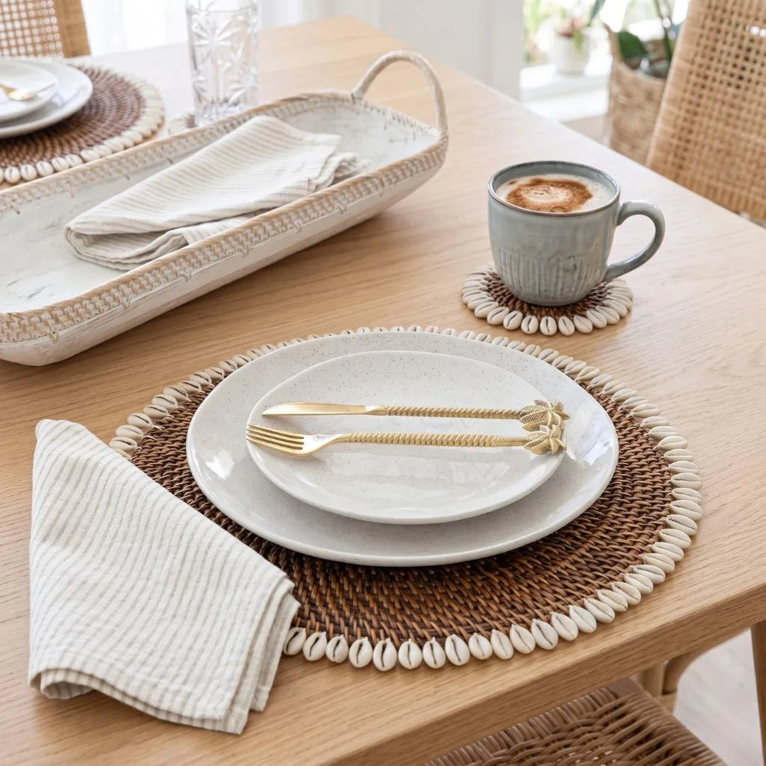 Dining table setting with plates, cutlery, and a cup of coffee on a wooden table.