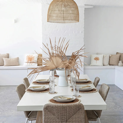 Dining area with a white table set for four, featuring plates, glasses, and decorative elements in a modern home setting.