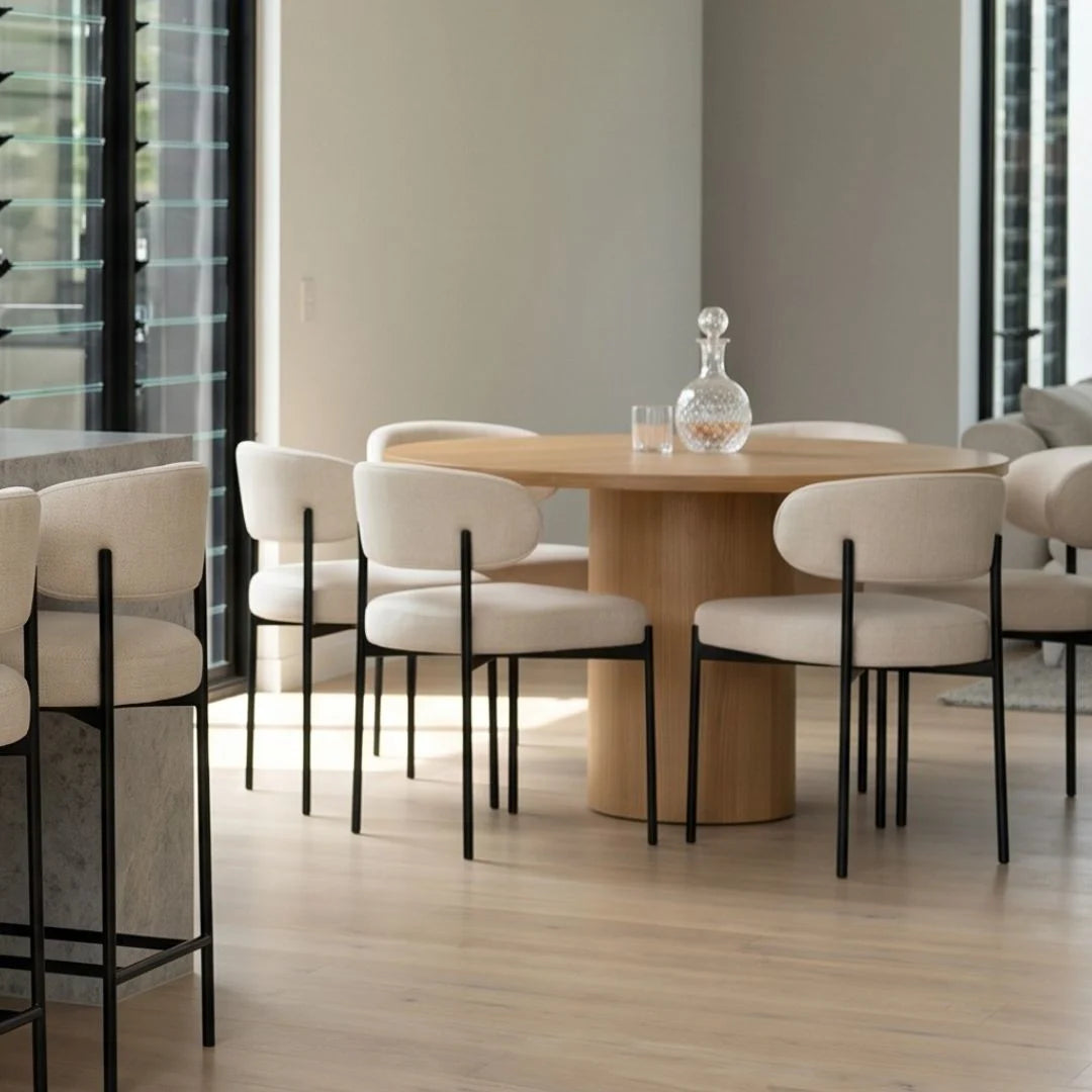 Dining area with round wooden table and white chairs in a modern interior.