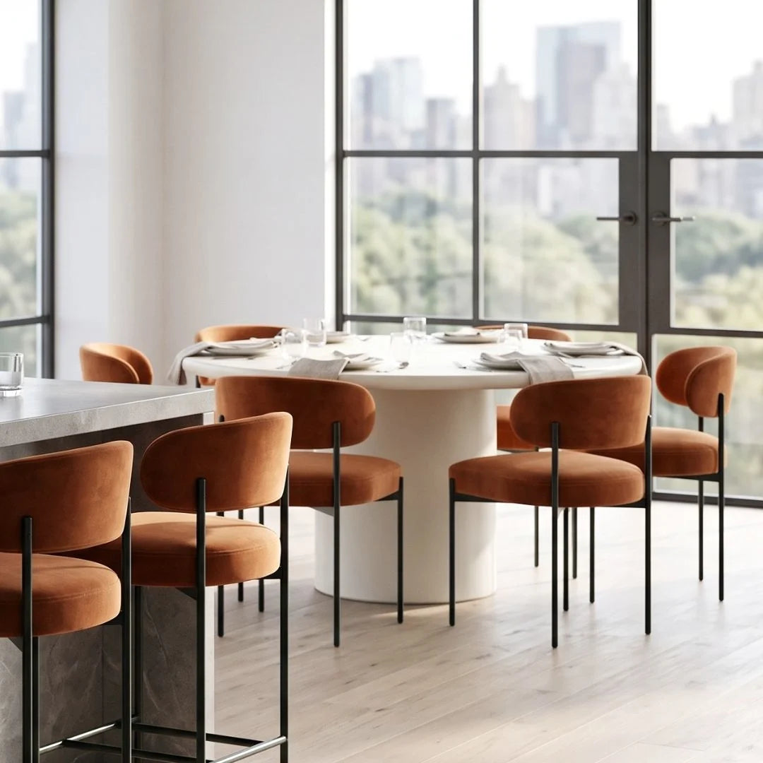 Modern dining area with round table and orange chairs in a room with large windows.
