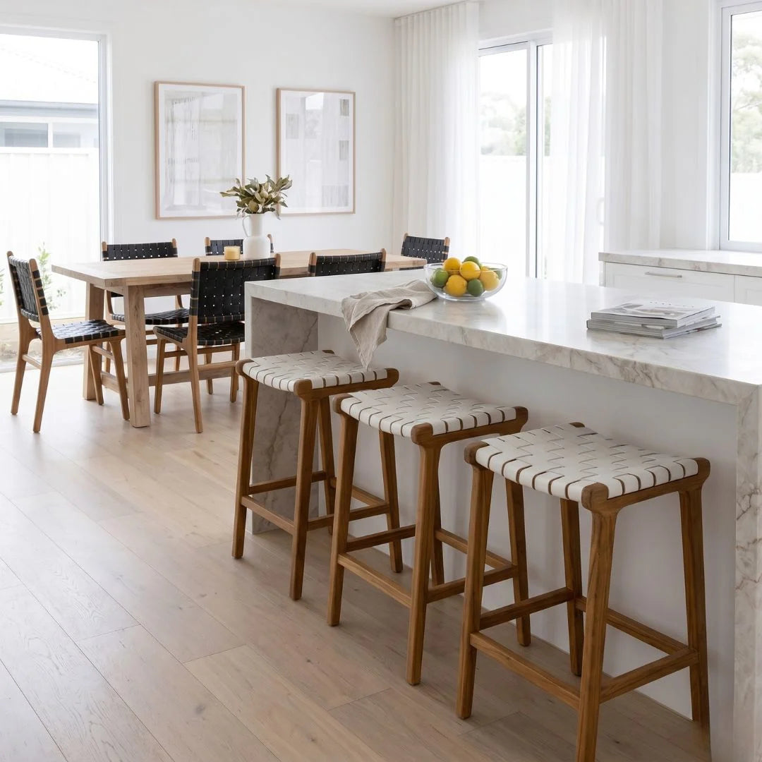 Modern kitchen with marble island, stools, and dining area.