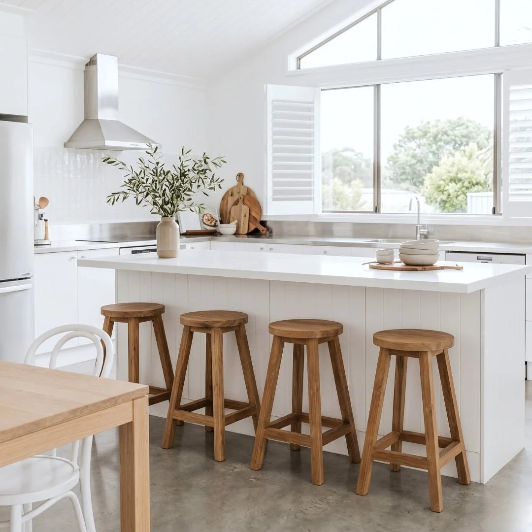 Sun Republic round teak counter stool in a row of four at a kitchen island bench in a modern light and bright kitchen