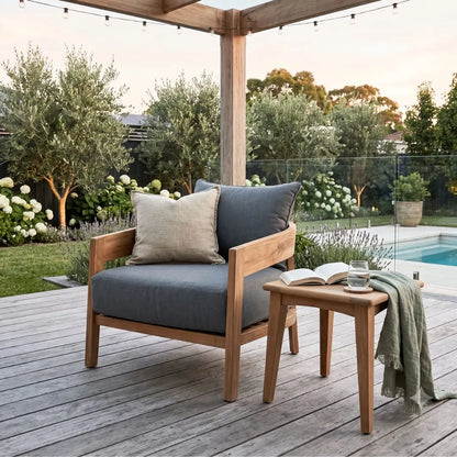 Outdoor seating area with a wooden chair and table on a deck, featuring a pool and garden in the background.