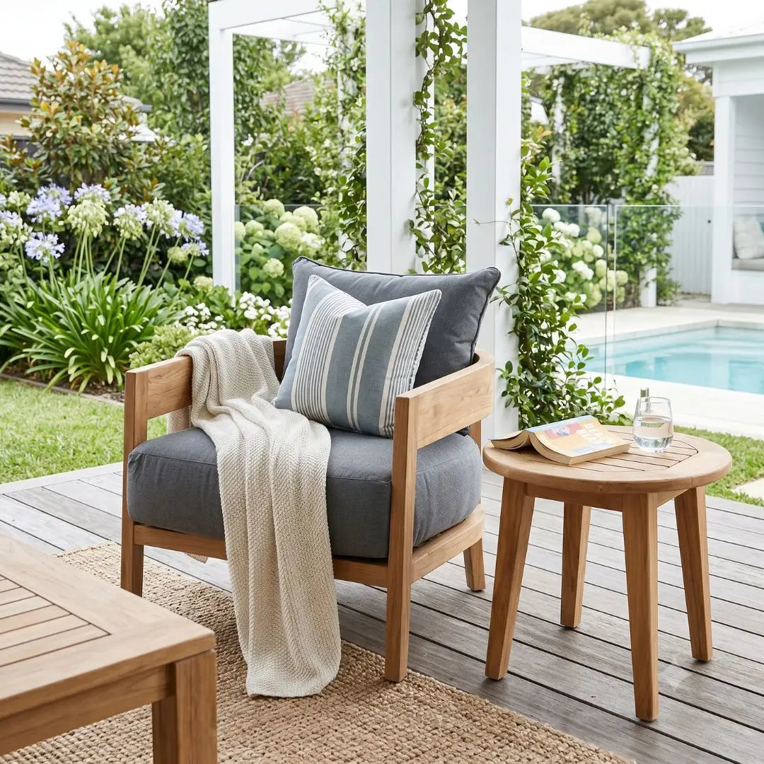 Outdoor seating area with a chair, table, and cushions on a wooden deck.