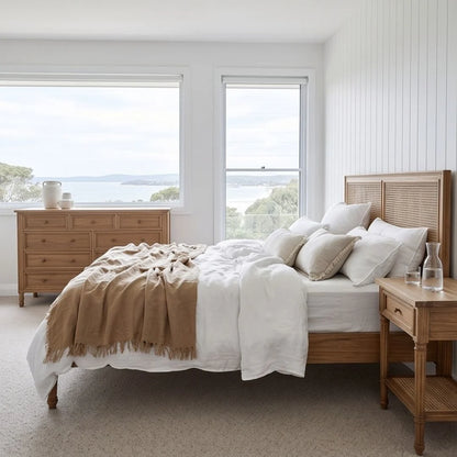 Bedroom with wooden bed, dresser, and nightstand with a view of water.
