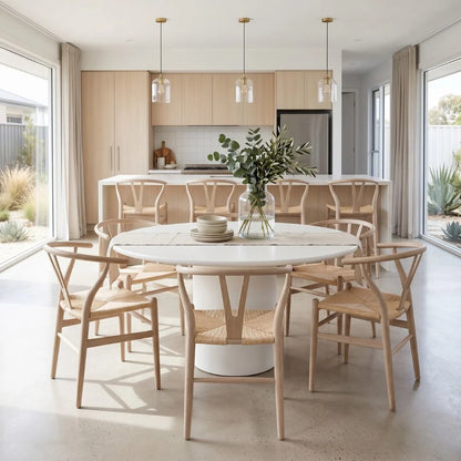 Modern kitchen with a round dining table and chairs, featuring a vase with greenery.