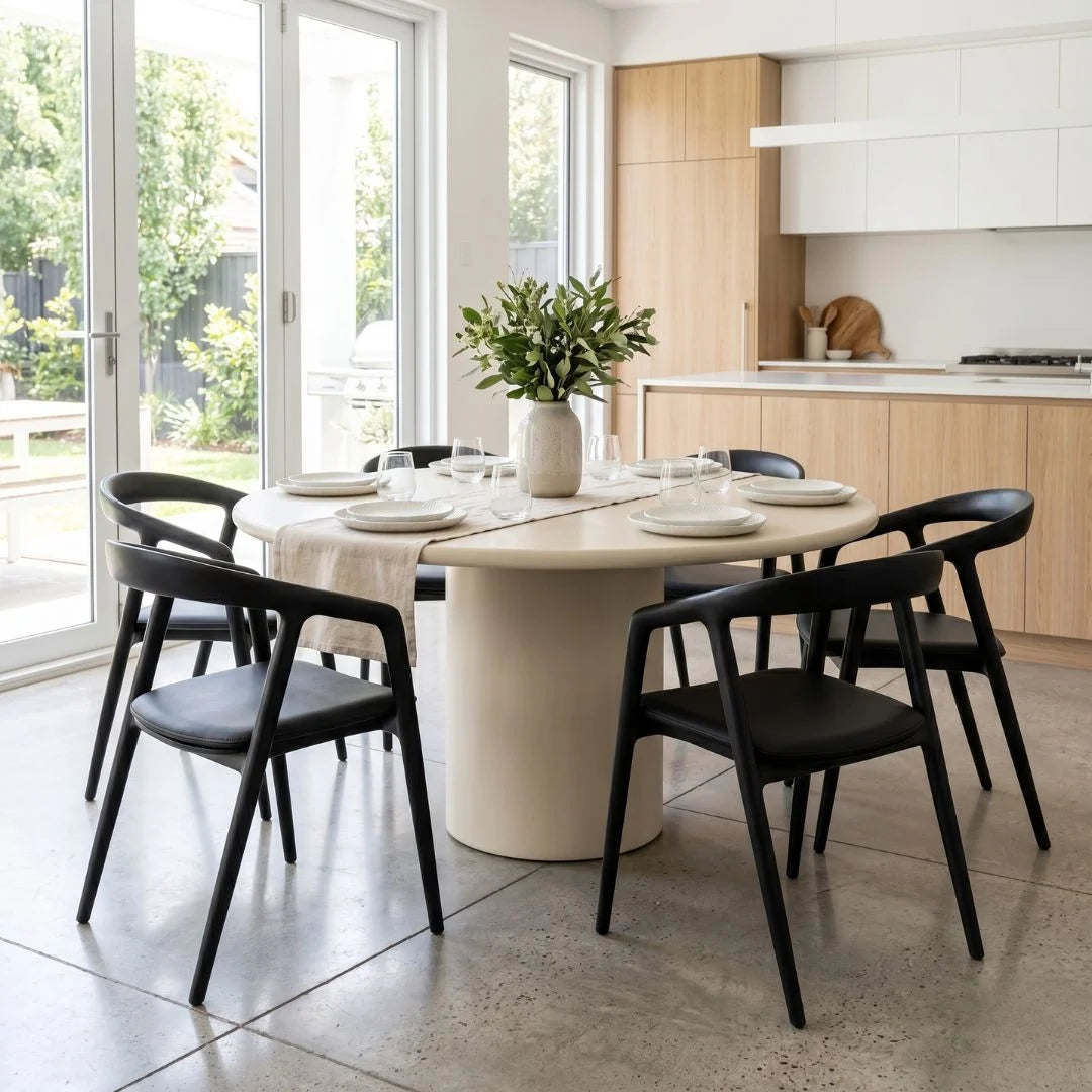 Dining area with a round table and black chairs in a modern kitchen.