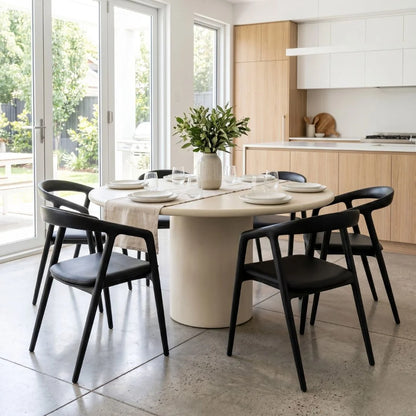 Dining area with a round table and black chairs in a modern kitchen.
