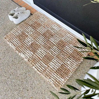 Textured doormat with shoes on a concrete floor next to a door.