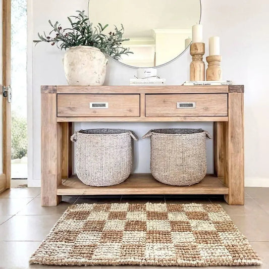 Wooden console table with two woven baskets and decorative items in a room.