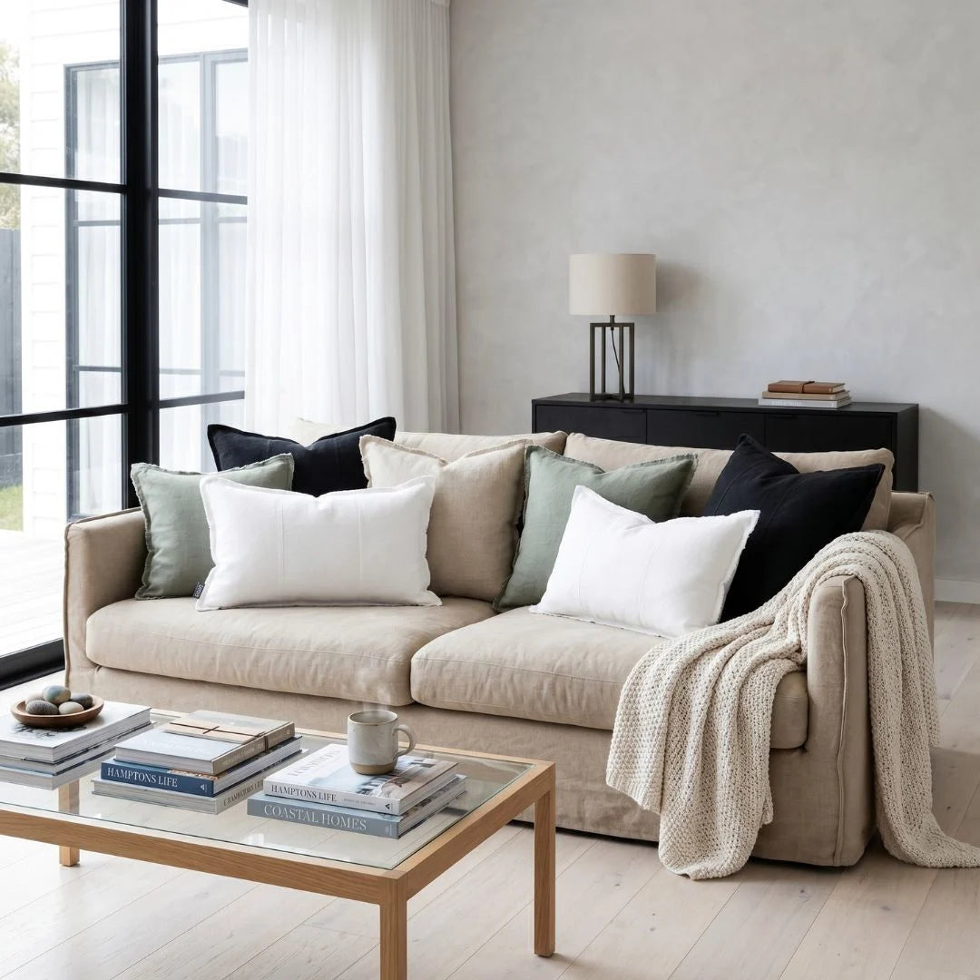 Beige sofa with decorative pillows and a blanket in a modern living room.