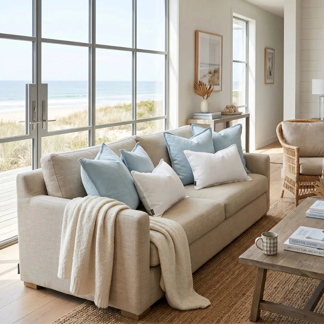 Beige sofa with decorative pillows in a living room with large windows.
