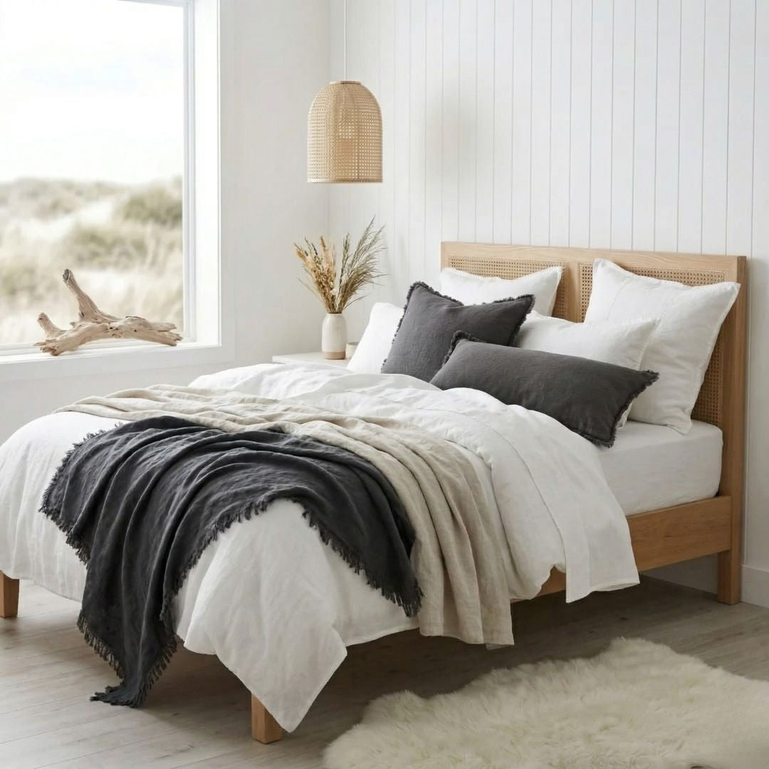 Neatly made bed with white bedding and gray and beige throw blanket in a bright bedroom.