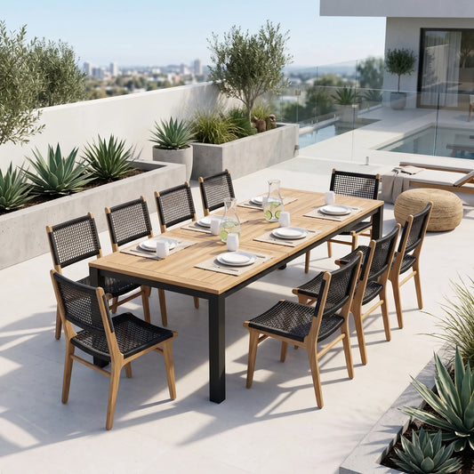 An outdoor dining set on a rooftop terrace, featuring a rectangular wooden table with black metal legs and eight matching chairs with black woven seats and wooden frames. The set is styled with tableware, including plates, glasses, and a water pitcher, set against a backdrop of a pool, city skyline, and green plants.