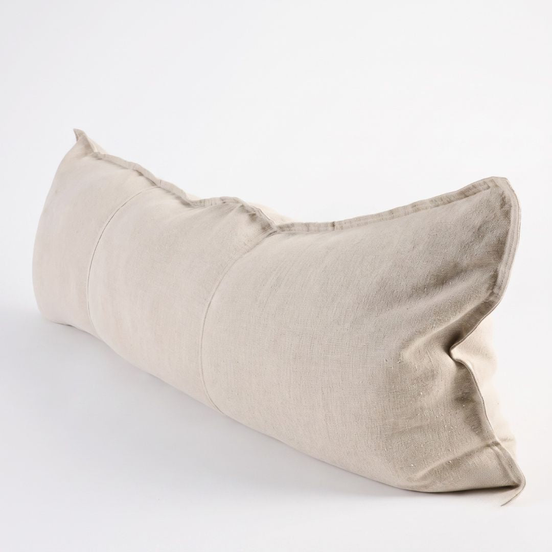 A rectangular lumbar pillow in a light beige linen fabric, shown at an angle on a clean white background.