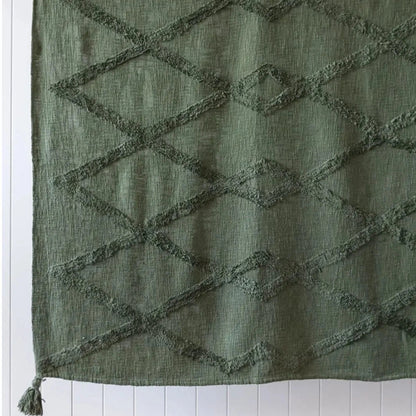An olive green textured fabric panel with a raised geometric diamond pattern and a tassel at the bottom, shown against a white paneled background.