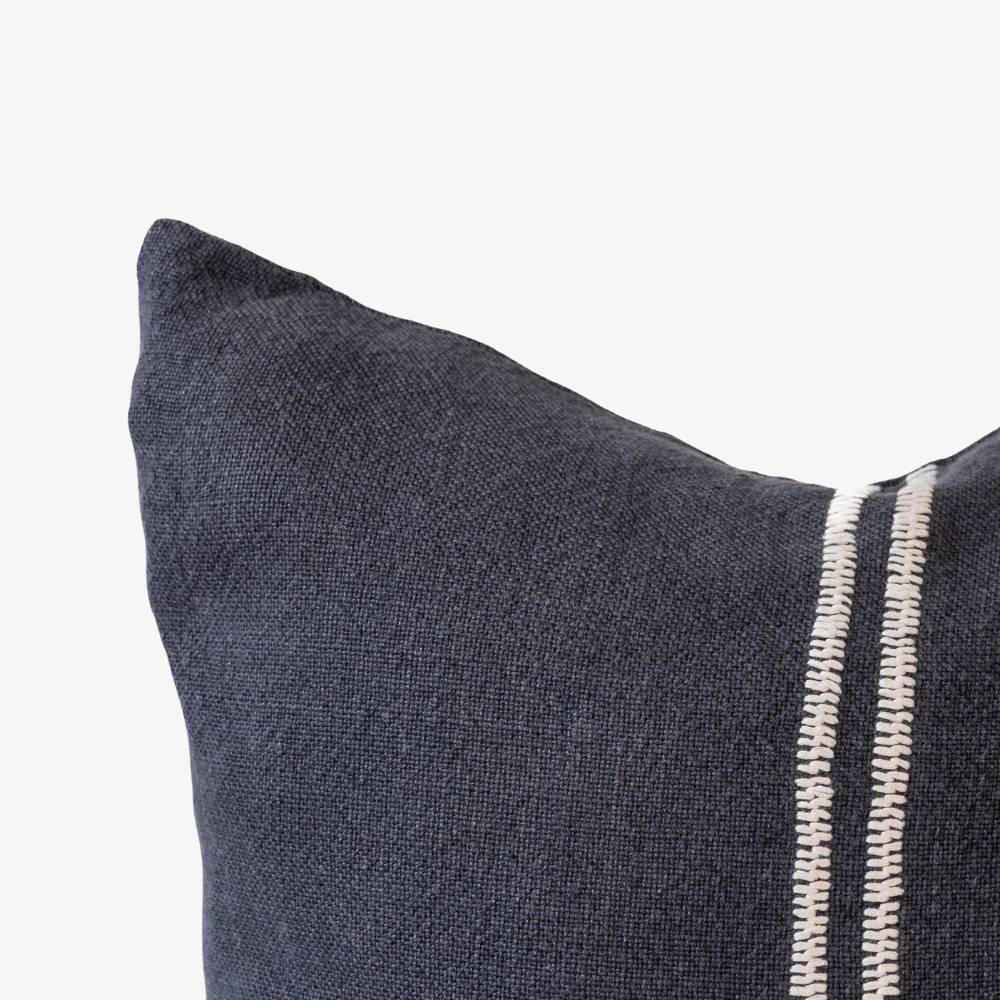 Dark navy pillow with white stitching on a light gray background