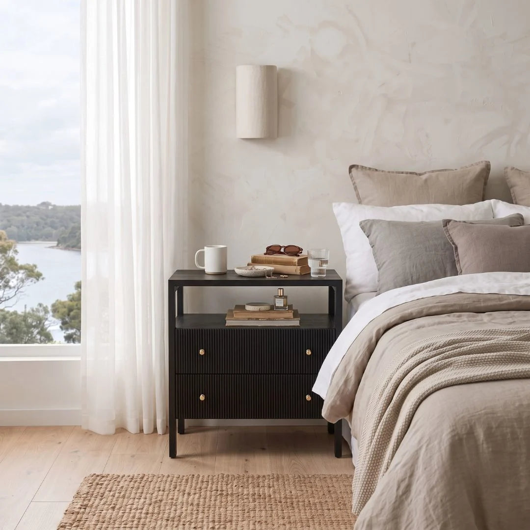 A modern black ribbed nightstand in a styled bedroom setting.