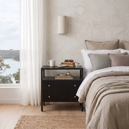 A modern black ribbed nightstand in a styled bedroom setting.