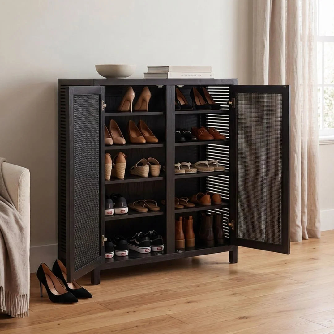 A tall black shoe cabinet with two open doors, filled with various shoes, set in a bright, modern room with light wood floors and beige curtains.