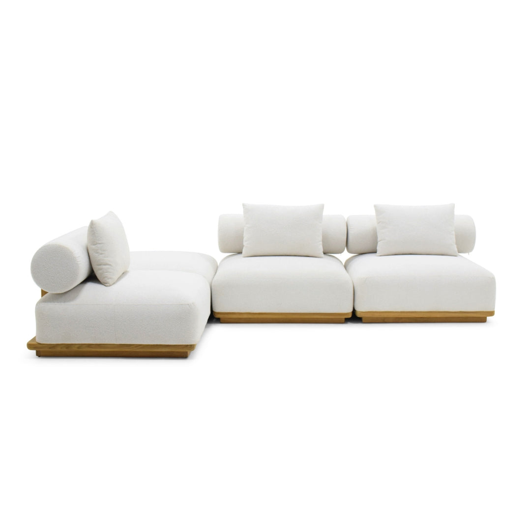 A modern modular sectional sofa with off-white cushions and light natural wood bases, shown on a plain white studio background.