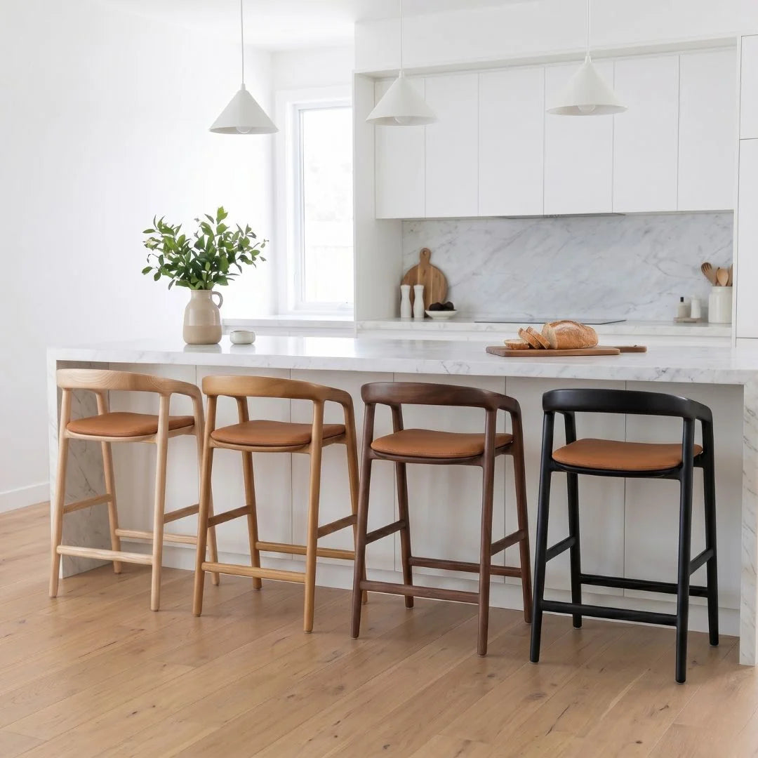 Four bar stools with different finishes in a kitchen setting.