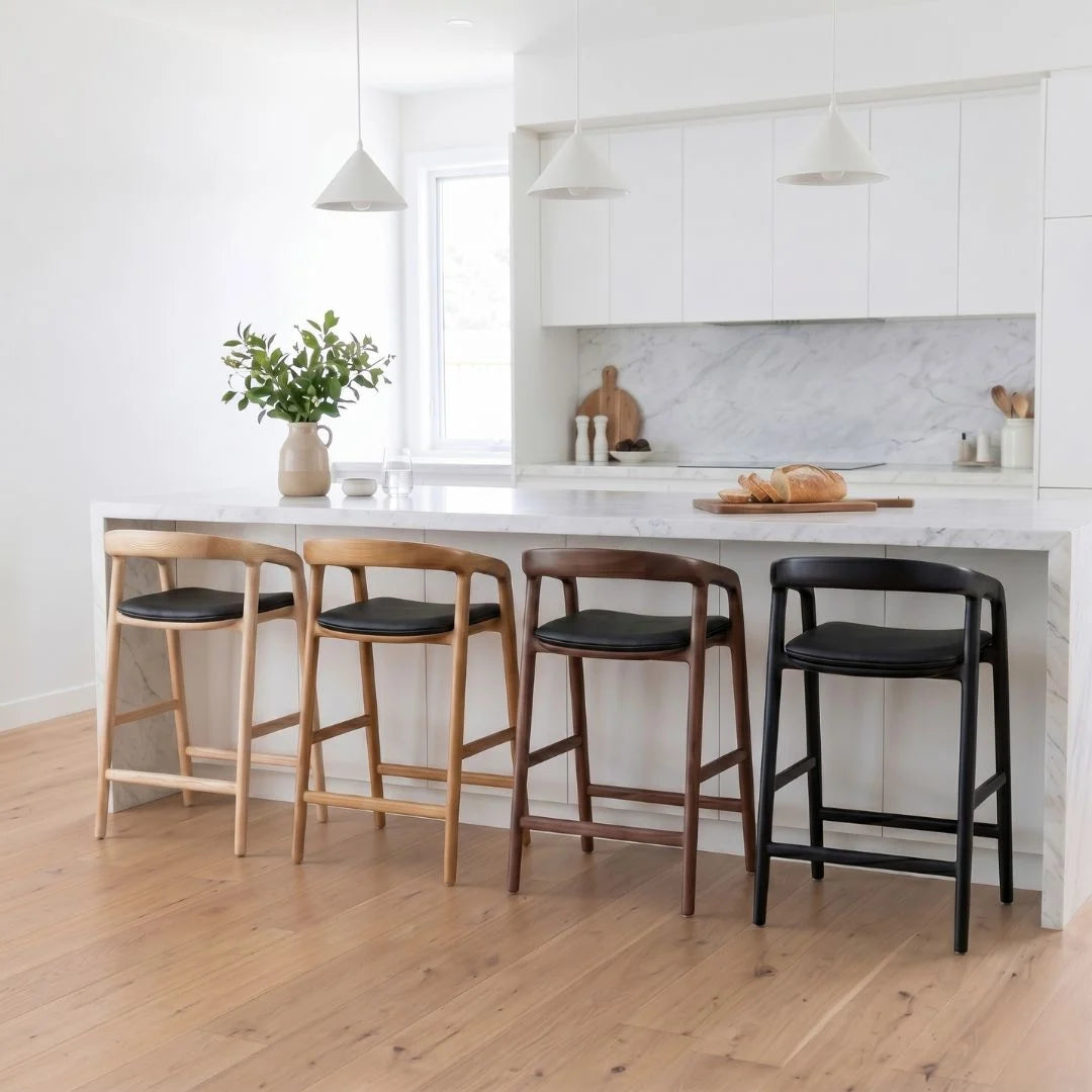 Four bar stools with different finishes in a modern kitchen setting.