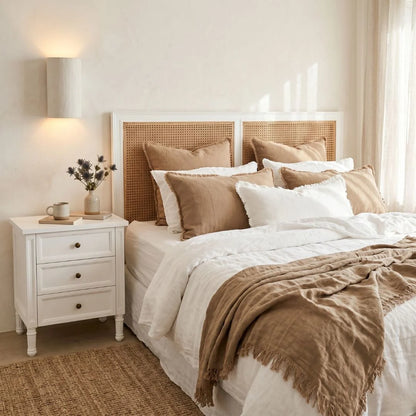 Neatly made bed with beige and white bedding in a bedroom setting.