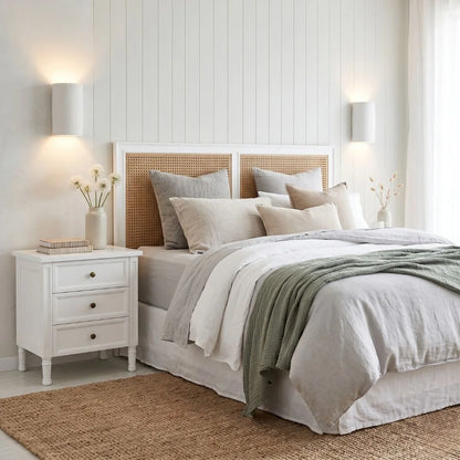 Neatly made bed with white bedding and a wooden headboard in a well-lit bedroom.