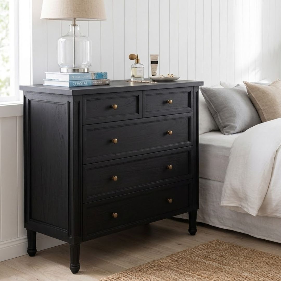 Black dresser with gold knobs in a bedroom setting