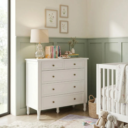 Nursery room with a white dresser and crib.