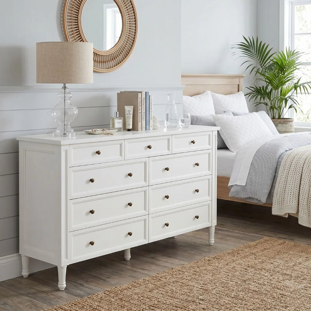 White dresser in a bedroom with a bed, lamp, and decor items.
