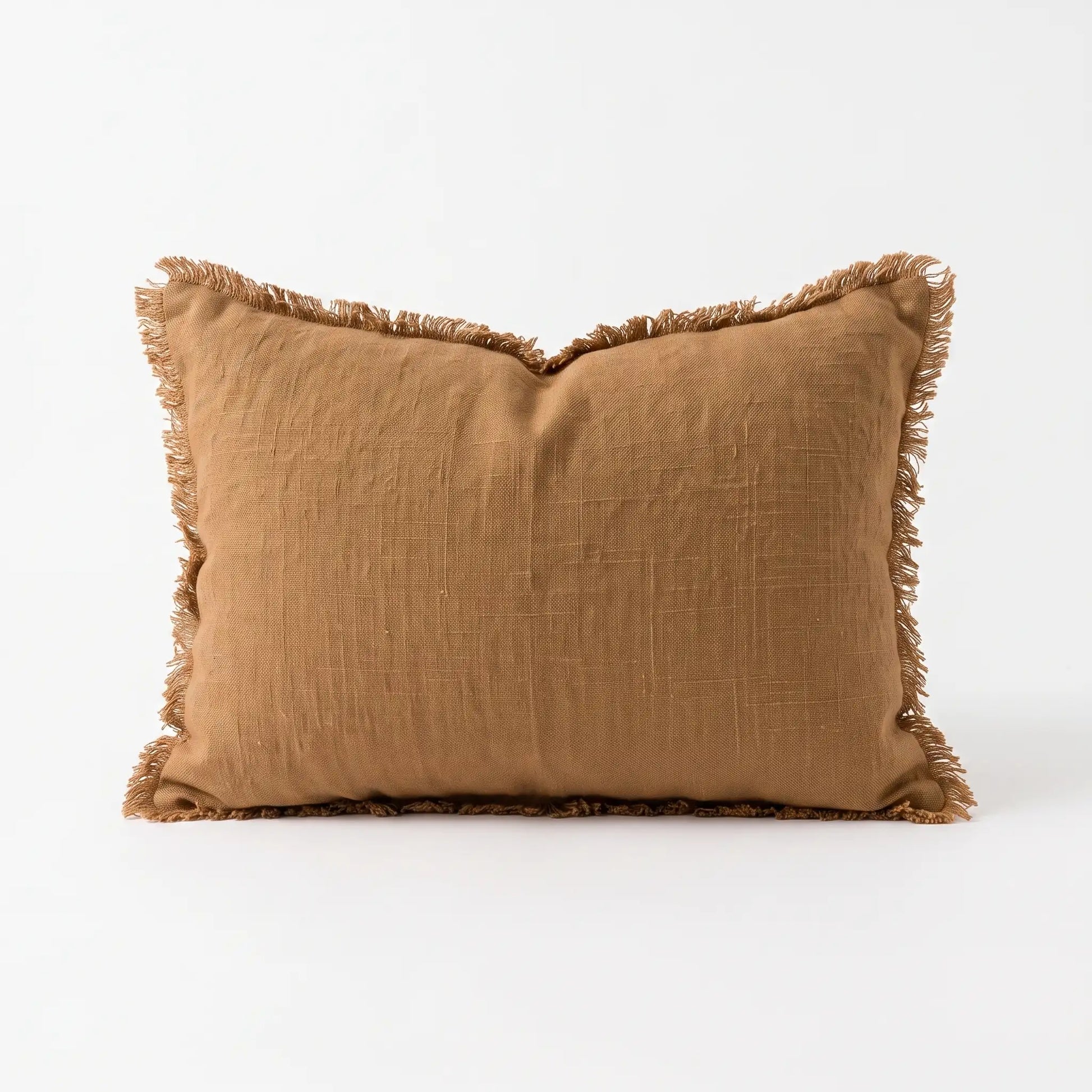 A square cinnamon tan throw pillow with fringed edges, made from a textured linen-like fabric, shown on a clean white background.