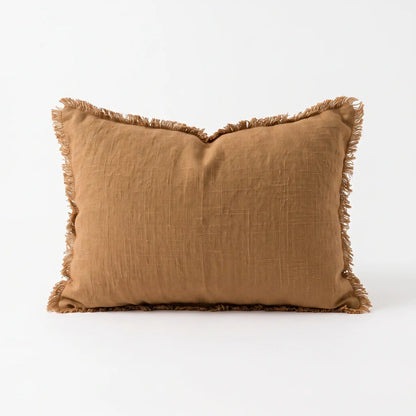 A square cinnamon tan throw pillow with fringed edges, made from a textured linen-like fabric, shown on a clean white background.